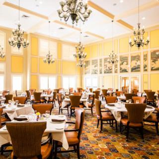 An elegant restaurant dining room with neatly set tables and chandeliers.