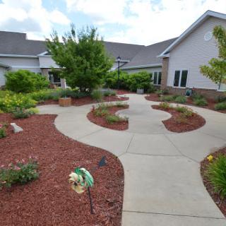 A beautifully landscaped garden with a winding pathway surrounded by lush plants and flowers.