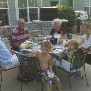 A family enjoying a meal together outdoors on a sunny day.