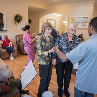 Seniors interacting with a caregiver in a communal setting.