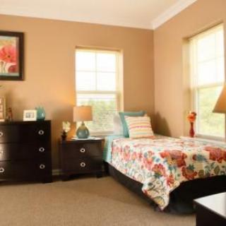A cozy bedroom with a single bed, colorful bedding, and matching decor.