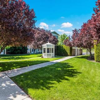 A scenic garden featuring a gazebo surrounded by lush grass and vibrant trees on a sunny day.