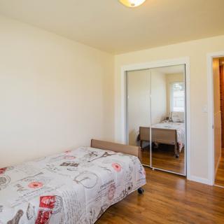 A cozy bedroom with a single bed, mirror closet, and wooden flooring.