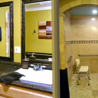 A well-designed bathroom with a large mirror, sink, and accessible shower area.