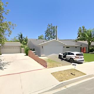 A suburban home with a driveway and parked car on a sunny day.