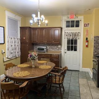 A cozy kitchen dining area featuring a wooden table, chairs, and modern appliances.