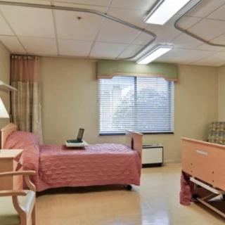 A hospital room with a single bed and window.