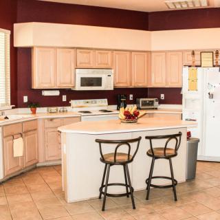 A modern kitchen with wooden cabinets, bar stools, and a central island.