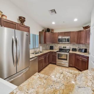A modern kitchen with stainless steel appliances and wooden cabinets, featuring granite countertops.