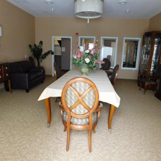 A well-furnished dining room with a long table surrounded by chairs, featuring a floral centerpiece.