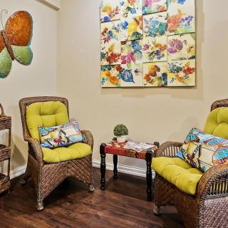 Cozy living room corner with wicker chairs and colorful artwork.