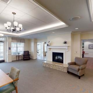 A spacious living room with a fireplace, armchairs, and a chandelier.
