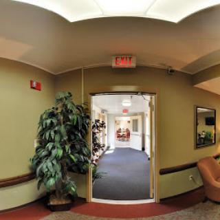 A view of an inviting interior hallway with a doorway leading to another space, complemented by greenery.