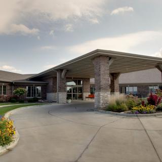 A well-maintained building entrance with a circular driveway and landscaped surroundings.