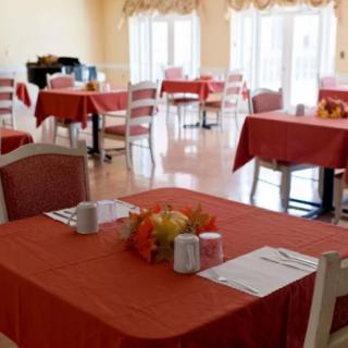 An elegantly set dining room with red tablecloths and neatly arranged tables and chairs.