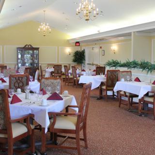 An elegant dining room with neatly arranged tables and chandeliers.