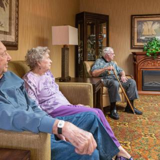 Elderly residents gather in the common area of a nursing home for a social moment.