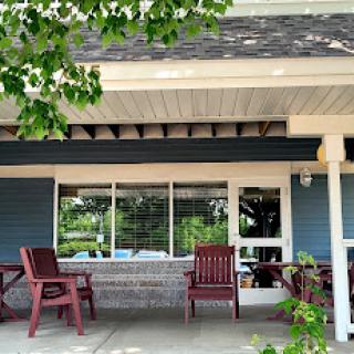 A cozy outdoor seating area in front of a building, surrounded by greenery.