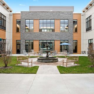 A modern building with a courtyard featuring a central fountain and seating area.