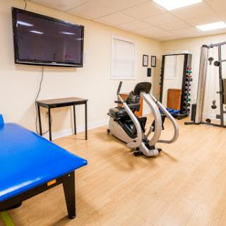 A well-equipped gym space featuring exercise machines, weights, and a television for workout guidance.