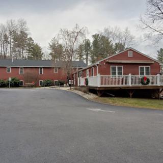 A red brick building complex with an adjacent road and trees under an overcast sky.