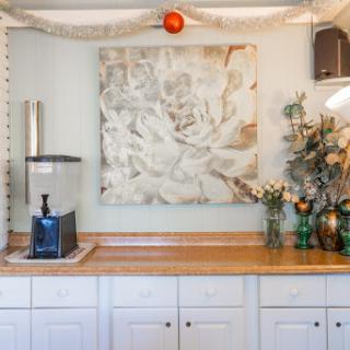 A cozy kitchen corner featuring floral artwork, a water dispenser, and decorative flowers.