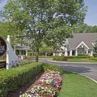 A scenic view of a building entrance with colorful flowers and lush greenery.