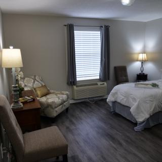 A cozy bedroom with modern decor including a bed, chair, and lamps.