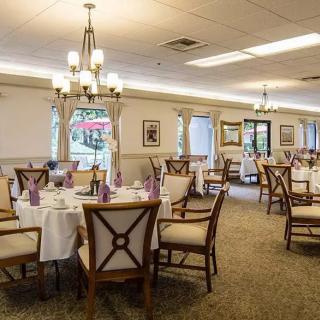 An elegant dining room with neatly set tables and chandeliers, offering a cozy atmosphere.