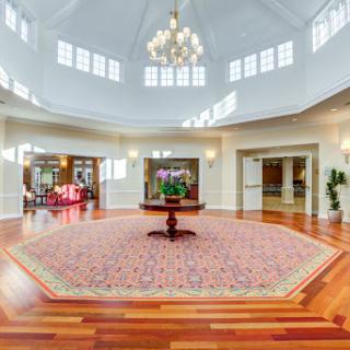 A spacious and elegantly designed lobby featuring a chandelier, wooden flooring, and decorative plants.