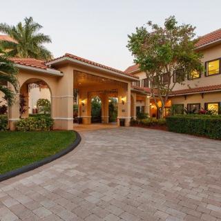 A picturesque driveway leading to a beautifully designed residential building surrounded by manicured landscaping.
