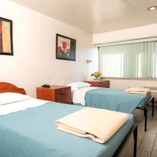 A simple hotel room with twin beds and minimalist decor.