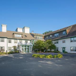 A well-maintained hotel building with a landscaped entrance and clear blue sky.
