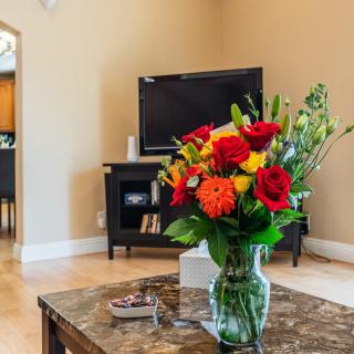 A cozy living room with a bouquet of colorful flowers on the coffee table and a television in the background.