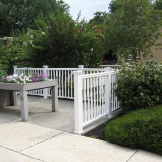 A serene outdoor patio with white fencing and lush greenery.
