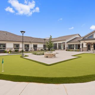 A modern building with a landscaped courtyard featuring a lawn and pathways under a clear blue sky.