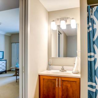 A modern bathroom featuring a wooden cabinet with a sink, a mirror above, and a blue patterned shower curtain.