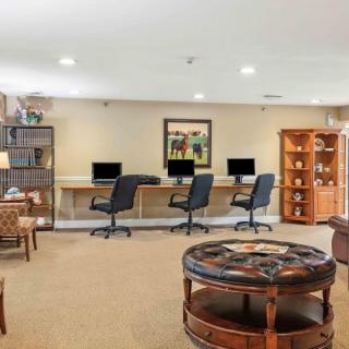 A modern office space featuring multiple computer workstations, comfortable seating, and a bookshelf.