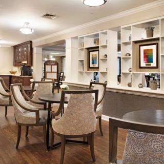A cozy dining area featuring elegant tables and chairs, with shelves displaying artwork and decorative items.