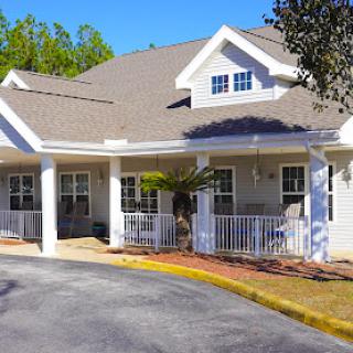 A charming residential building with a porch and landscaped surroundings.
