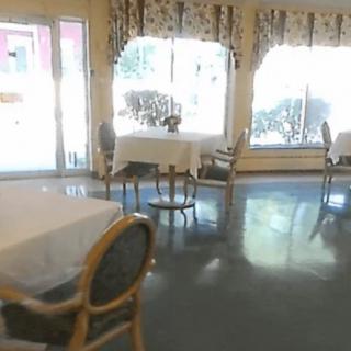 A bright restaurant interior with tables and chairs arranged near large windows.