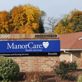 A nursing home facility sign surrounded by autumn foliage.