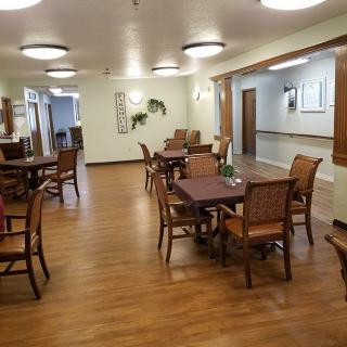 A spacious dining area with several tables and chairs, featuring wooden flooring and modern lighting.