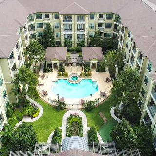 Aerial view of a modern apartment complex featuring a central swimming pool and well-maintained landscaping.