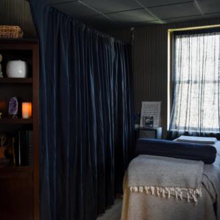 A tranquil massage room with soft lighting, a comfortable bed, and calming decor.