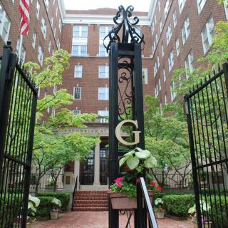 An entrance gate with a prominent 'G' leading to a brick building, surrounded by greenery.