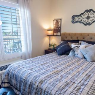 A cozy bedroom with a neatly made bed, decorative pillows, and soft lighting.