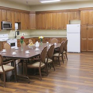 A kitchen and dining area featuring wooden cabinets, a large table with chairs, and standard kitchen appliances.