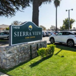 The image shows the sign for Sierra View apartments located next to a parking lot filled with cars on a sunny day.