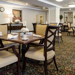 An elegant dining room featuring neatly arranged tables and chairs with a carpeted floor.